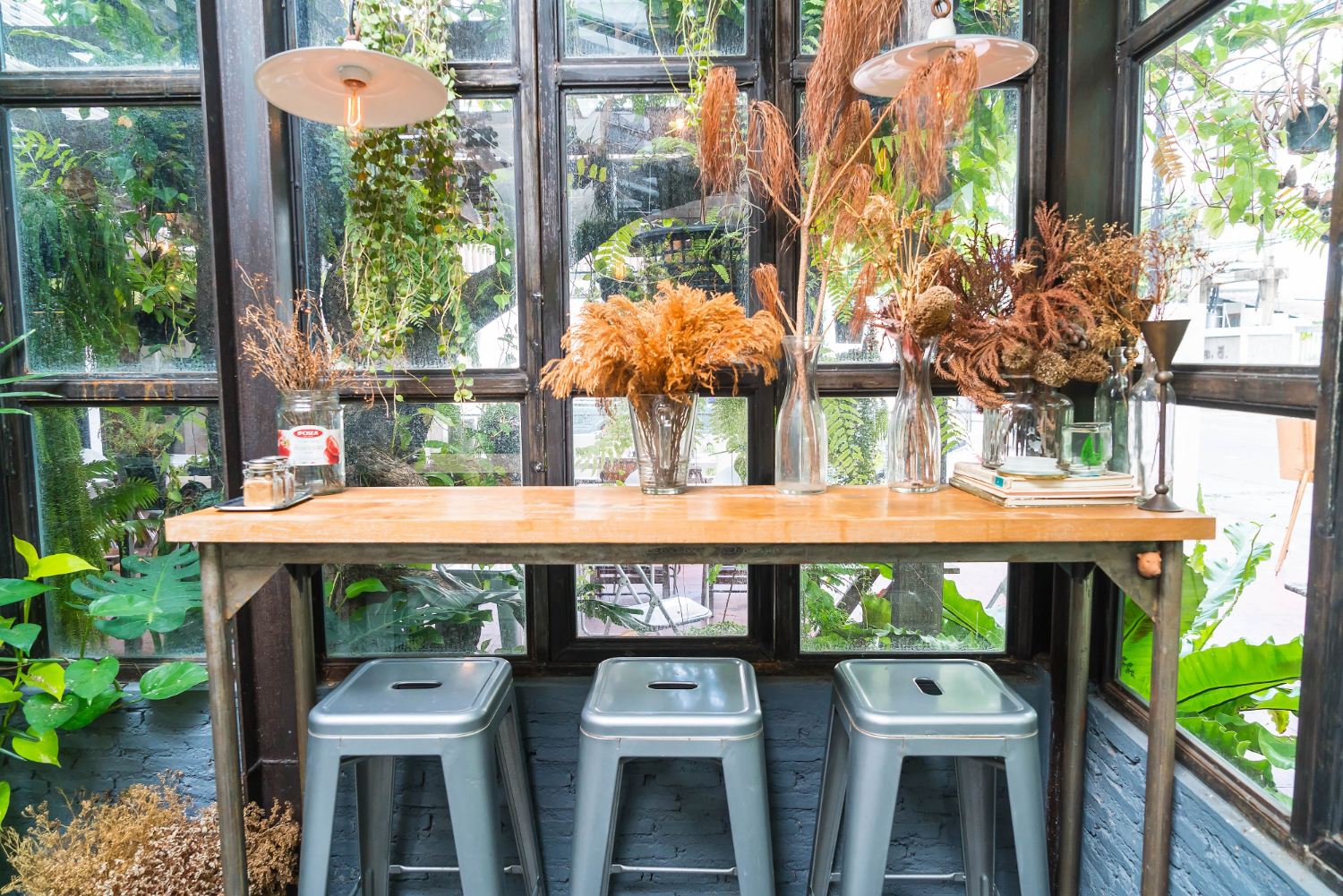 Coin café chaleureux les-rives-des-renards avec table en bois, fleurs séchées et vue verdoyante dans le tarn
